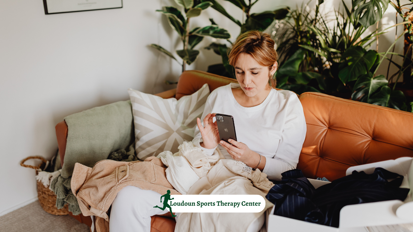 women sitting on the couch looking at her phone wrapped in a blanker